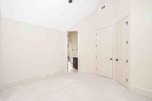 unfurnished bedroom with light carpet, vaulted ceiling, ensuite bath, and ceiling fan