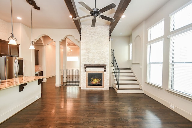 unfurnished living room featuring ceiling fan, dark hardwood / wood-style flooring, and a fireplace