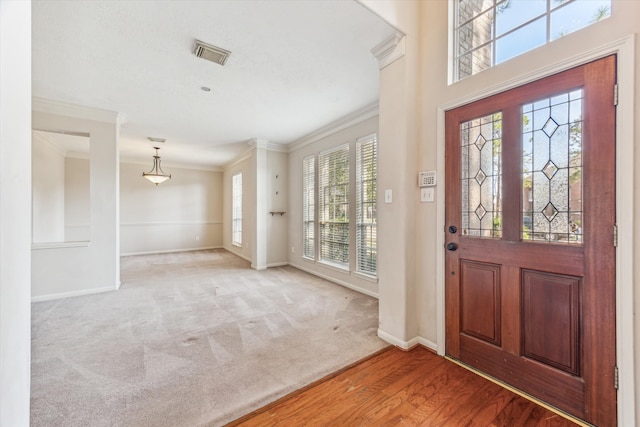 foyer entrance with crown molding, hardwood / wood-style floors, and a wealth of natural light