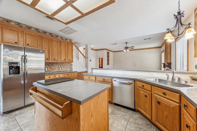 kitchen with ceiling fan, sink, a kitchen island, decorative light fixtures, and appliances with stainless steel finishes