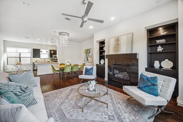 living room featuring ceiling fan, built in features, and dark hardwood / wood-style flooring