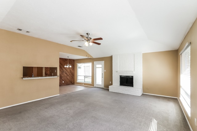 unfurnished living room with carpet floors, ceiling fan with notable chandelier, vaulted ceiling, and a fireplace