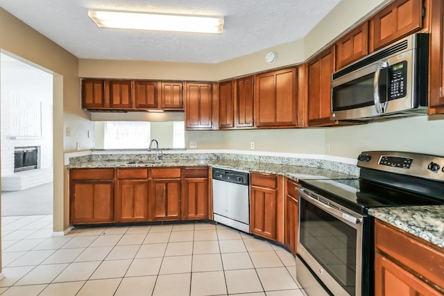 kitchen featuring appliances with stainless steel finishes, light stone counters, sink, and a textured ceiling