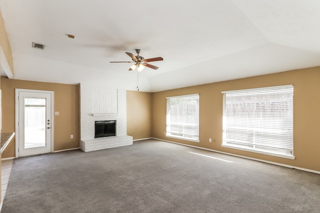 unfurnished living room with a brick fireplace, ceiling fan, carpet floors, and vaulted ceiling