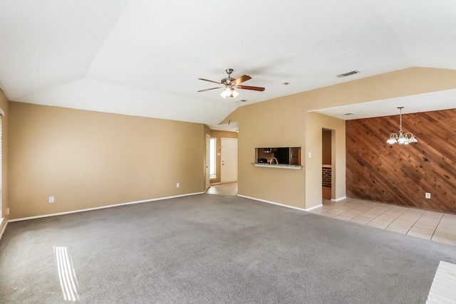 unfurnished living room with light colored carpet, ceiling fan with notable chandelier, wood walls, and vaulted ceiling