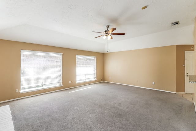 spare room with lofted ceiling, ceiling fan, carpet, and a textured ceiling