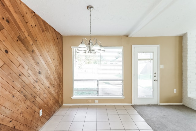 unfurnished dining area with wooden walls, beam ceiling, a chandelier, and light tile patterned floors