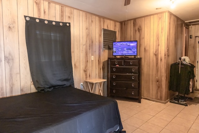 bedroom with wooden walls, ceiling fan, and light tile patterned floors