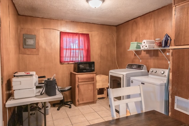 clothes washing area featuring independent washer and dryer, light tile patterned floors, wooden walls, and a textured ceiling