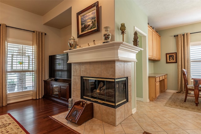 living room with a textured ceiling, a tiled fireplace, and light hardwood / wood-style floors