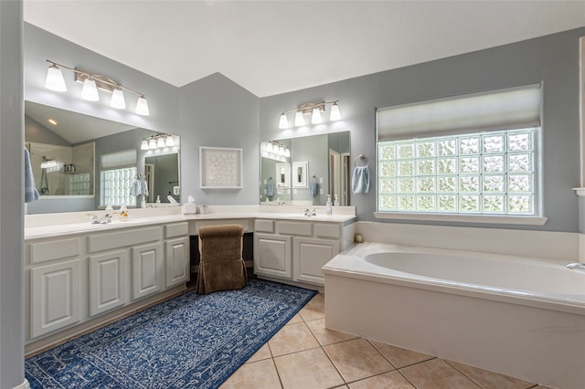 bathroom with tile patterned floors, a tub, vaulted ceiling, and vanity