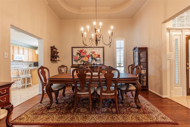 dining area featuring ornamental molding, hardwood / wood-style flooring, a tray ceiling, and an inviting chandelier