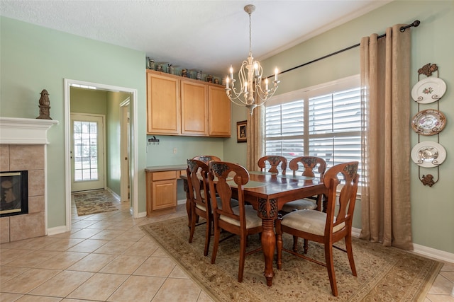 dining room with a textured ceiling, a fireplace, a chandelier, and light tile patterned floors