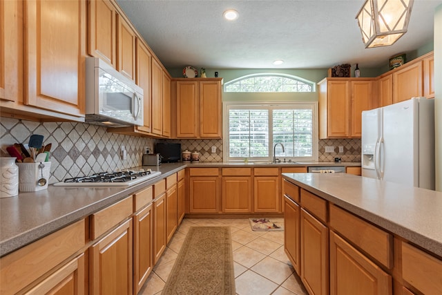 kitchen with decorative backsplash, white appliances, sink, and light tile patterned floors