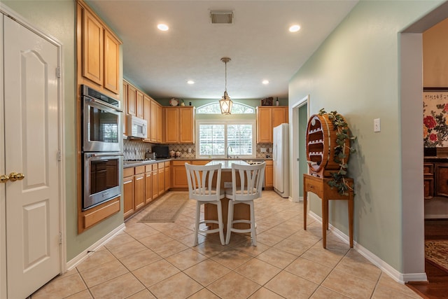 kitchen with light tile patterned flooring, a breakfast bar area, stainless steel appliances, hanging light fixtures, and a center island