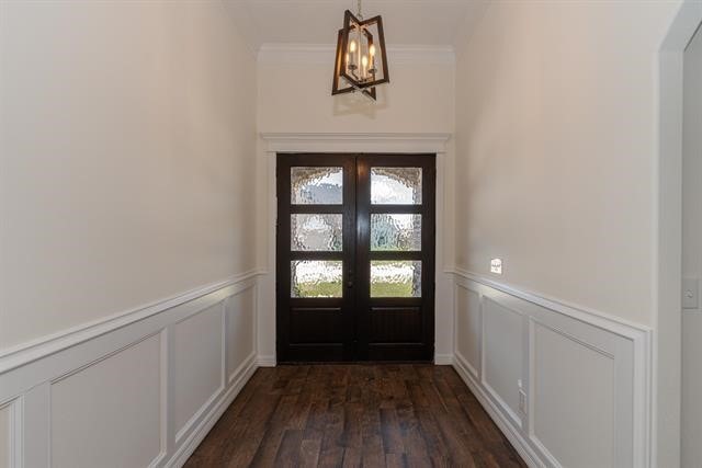 entryway with french doors, an inviting chandelier, dark hardwood / wood-style floors, and ornamental molding