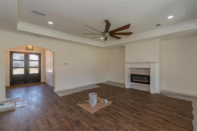 unfurnished living room with ceiling fan, french doors, a tray ceiling, dark hardwood / wood-style floors, and crown molding