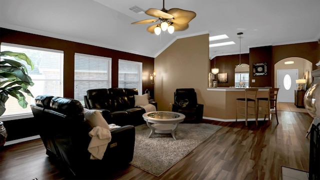 living room featuring ceiling fan, ornamental molding, dark hardwood / wood-style floors, and lofted ceiling with skylight