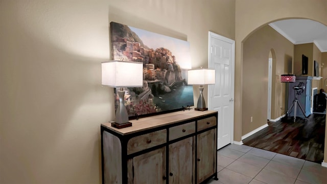 hallway with crown molding and light tile patterned floors