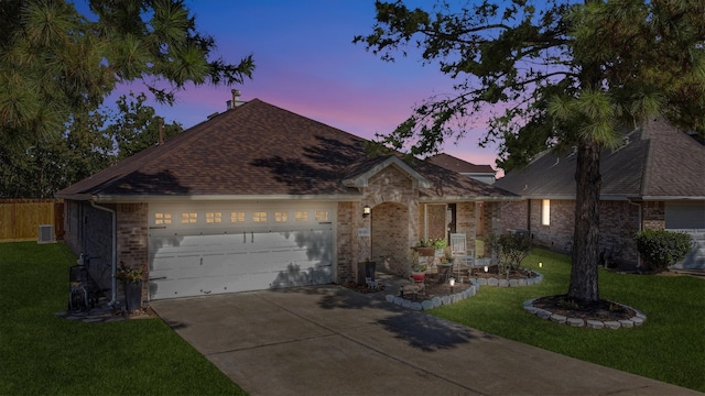 single story home with a garage, cooling unit, and a yard