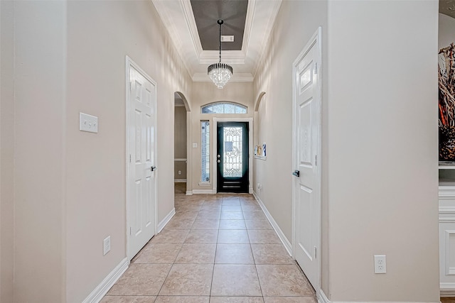 tiled entrance foyer featuring a chandelier, ornamental molding, and a tray ceiling