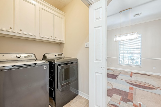 laundry room featuring cabinets, light tile patterned floors, crown molding, and washing machine and clothes dryer