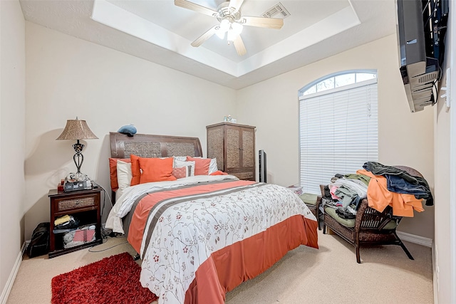 carpeted bedroom featuring a tray ceiling and ceiling fan