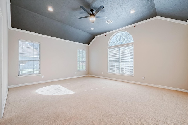 empty room featuring ceiling fan, light colored carpet, a textured ceiling, vaulted ceiling, and ornamental molding