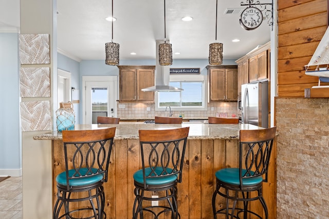 kitchen with light stone countertops, crown molding, decorative backsplash, and stainless steel refrigerator with ice dispenser