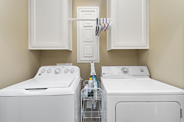 laundry room featuring washer and dryer and cabinets