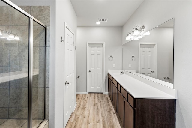 bathroom with hardwood / wood-style floors, walk in shower, and vanity