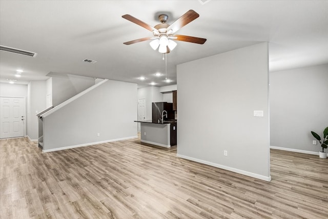 unfurnished living room featuring ceiling fan and light hardwood / wood-style floors