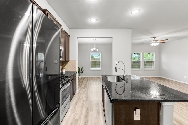 kitchen with hanging light fixtures, sink, a kitchen island with sink, appliances with stainless steel finishes, and light hardwood / wood-style floors