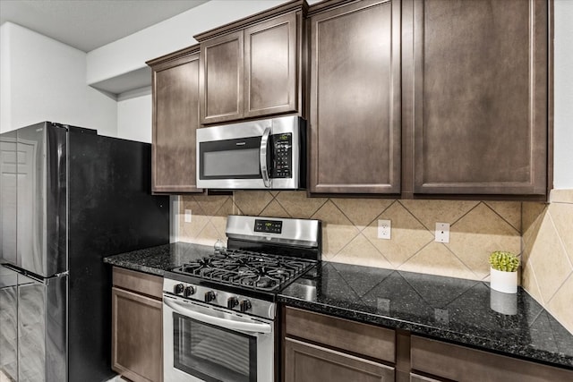 kitchen with stainless steel appliances, dark stone counters, backsplash, and dark brown cabinets