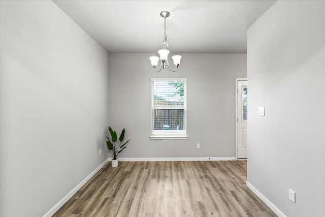 empty room with a chandelier and light wood-type flooring