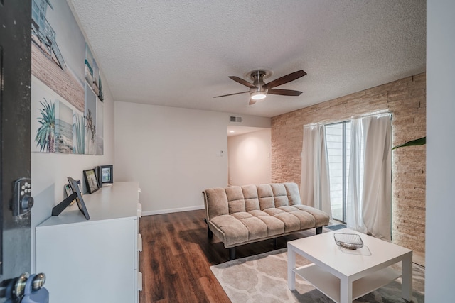 living room with ceiling fan, dark wood-type flooring, and a textured ceiling