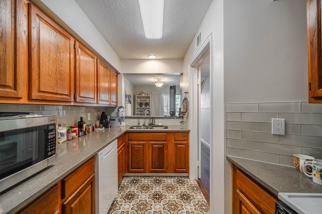 kitchen with light tile patterned floors, sink, a textured ceiling, dishwasher, and decorative backsplash