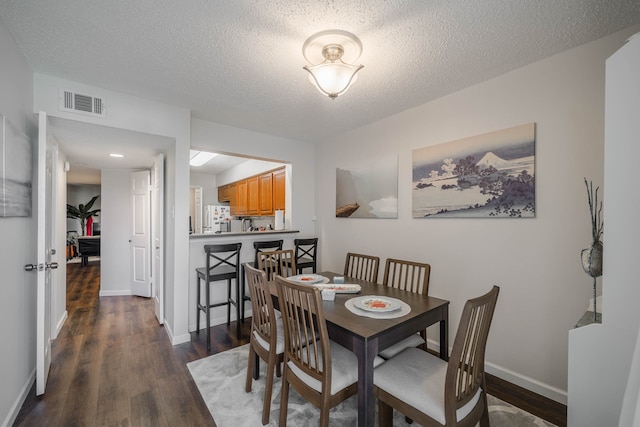 dining space with dark wood-type flooring and a textured ceiling