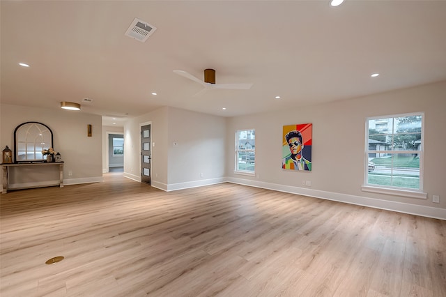 unfurnished living room with light wood-type flooring, a healthy amount of sunlight, and ceiling fan