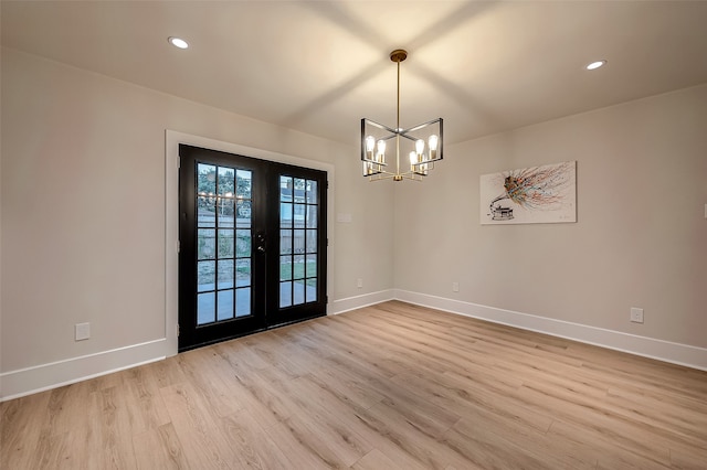 unfurnished dining area with french doors, a notable chandelier, and light wood-type flooring