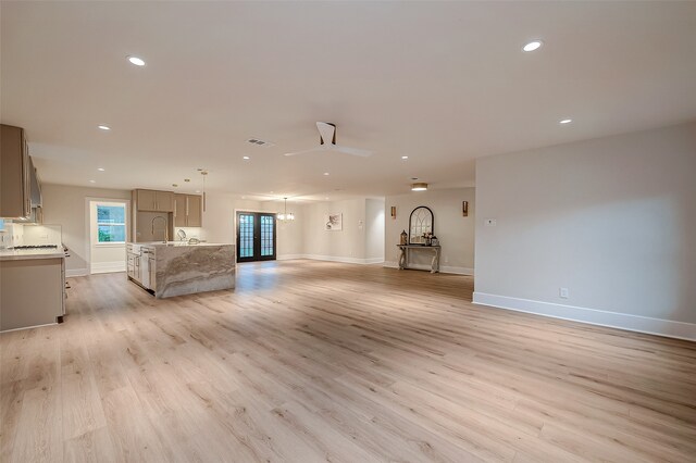 unfurnished living room with sink, french doors, light wood-type flooring, and ceiling fan