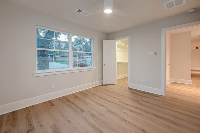 unfurnished bedroom featuring a closet, light hardwood / wood-style flooring, a spacious closet, and ceiling fan