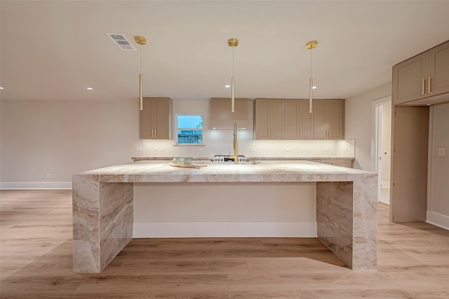 kitchen featuring light hardwood / wood-style floors, pendant lighting, and an island with sink