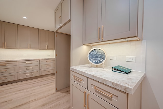 kitchen featuring gray cabinetry, light hardwood / wood-style floors, and tasteful backsplash