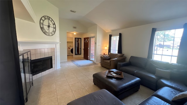 tiled living room with a tile fireplace, washer / clothes dryer, and vaulted ceiling