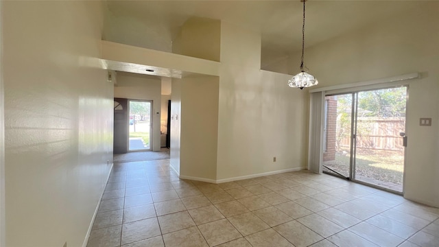 tiled empty room featuring a wealth of natural light, high vaulted ceiling, and a chandelier