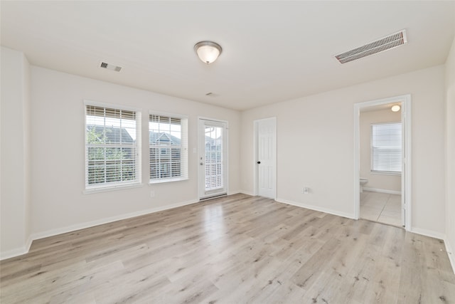 spare room featuring a wealth of natural light and light hardwood / wood-style flooring