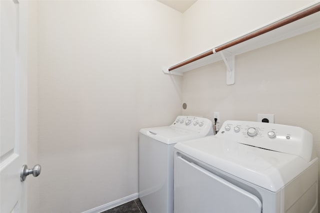 laundry room with washing machine and clothes dryer and dark tile patterned flooring