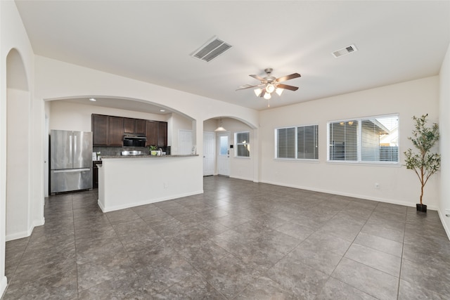 unfurnished living room with dark tile patterned floors and ceiling fan