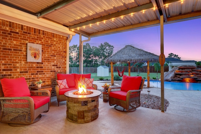 patio terrace at dusk with a gazebo, a shed, and an outdoor living space with a fire pit